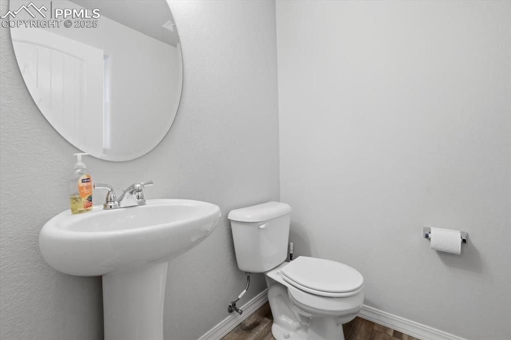 Half bathroom featuring wood finished floors and a textured wall