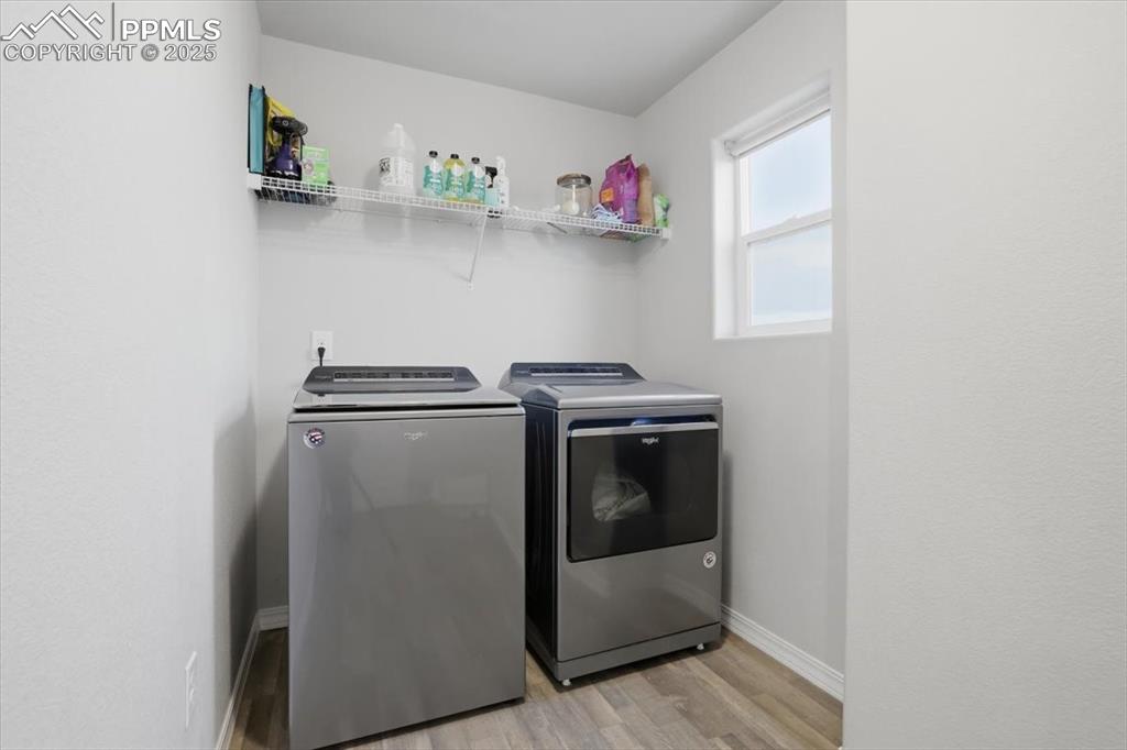 Laundry area with light wood finished floors and washer and dryer