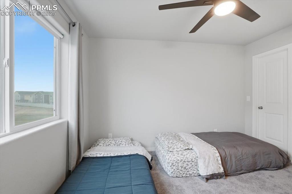 Carpeted bedroom featuring a ceiling fan