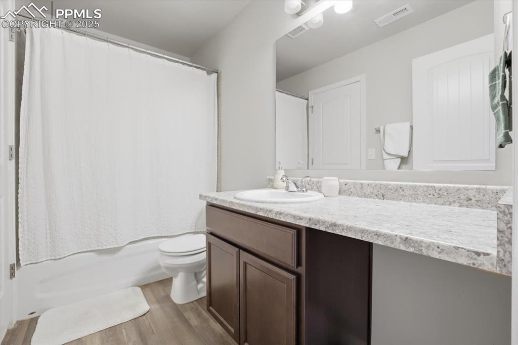 Bathroom with light wood-style flooring, vanity, and shower / tub combo