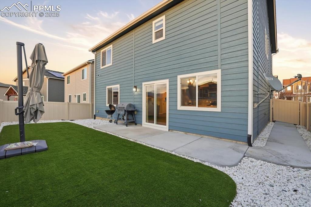 Back of house at dusk with a fenced backyard and a patio area