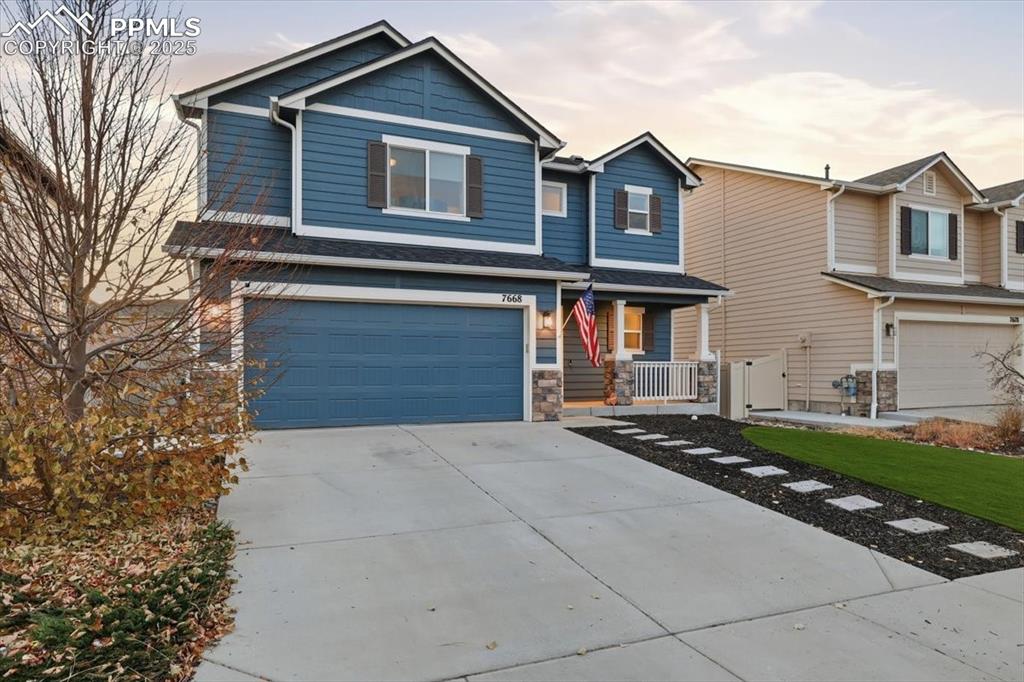 View of front of home featuring concrete driveway, a garage, and stone siding