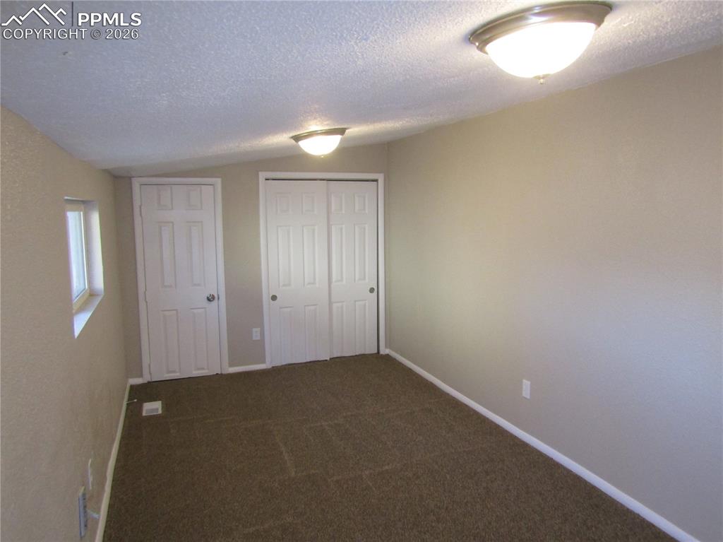 Unfurnished bedroom featuring a closet and dark carpet