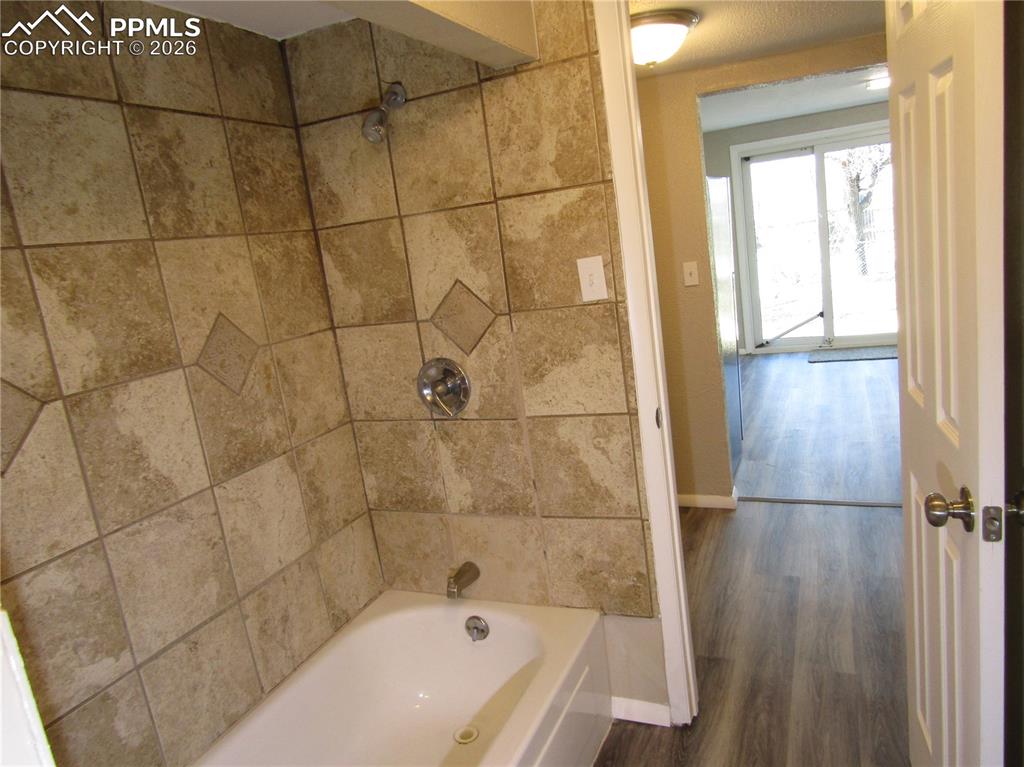 Full bathroom featuring washtub / shower combination and dark wood-style floors