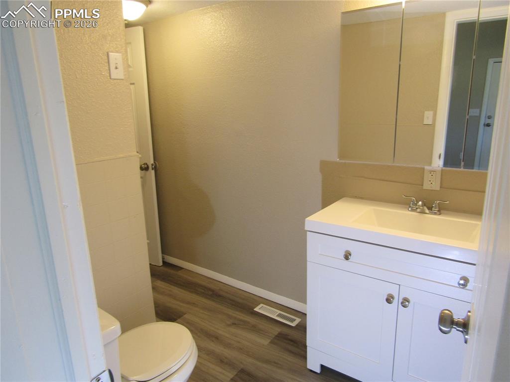 Half bathroom featuring vanity, dark wood finished floors, and a textured wall