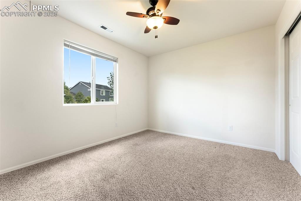 Carpeted empty room with ceiling fan and baseboards