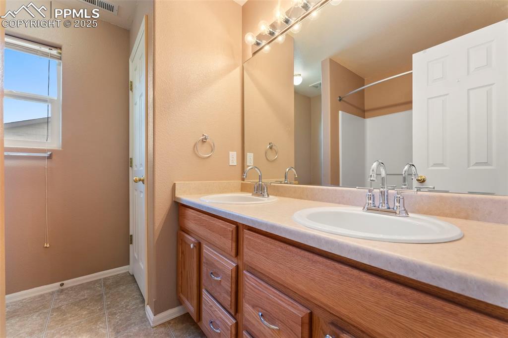 Full bathroom featuring double vanity and light tile patterned flooring