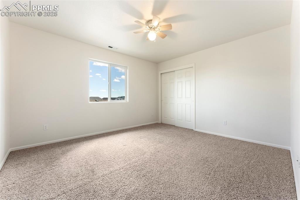 Unfurnished bedroom featuring carpet flooring, a closet, and a ceiling fan