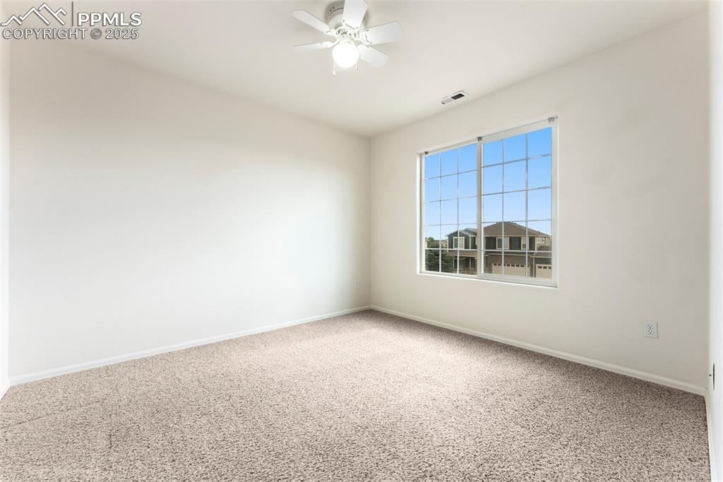 Carpeted spare room featuring baseboards and a ceiling fan