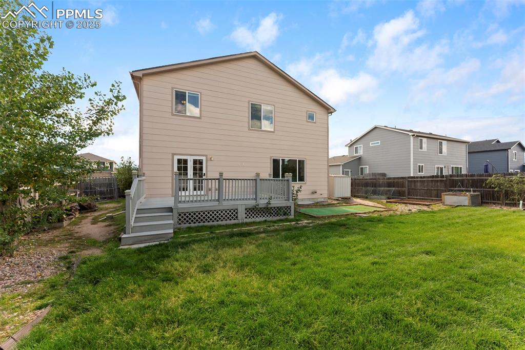 Rear view of house featuring a fenced backyard and a wooden deck