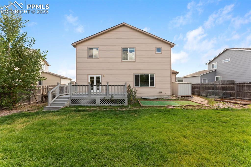 Back of house with a fenced backyard and a deck
