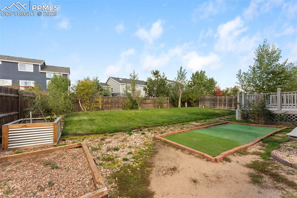 Fenced backyard with a vegetable garden and a patio area