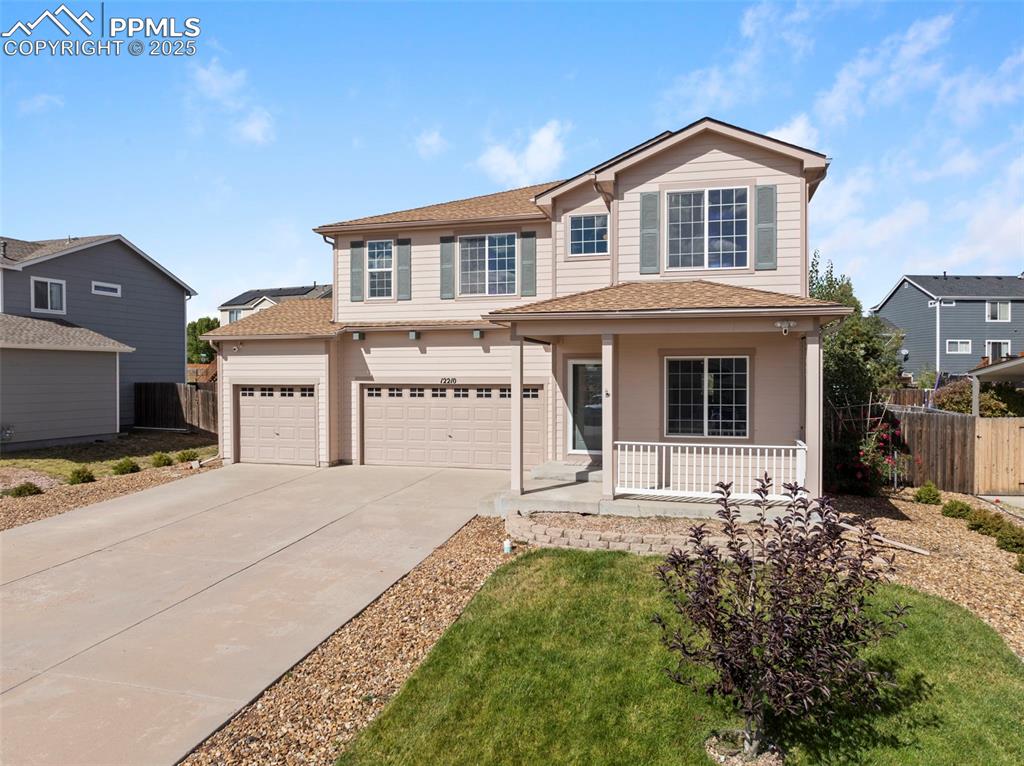 Traditional home with covered porch, driveway, and a shingled roof