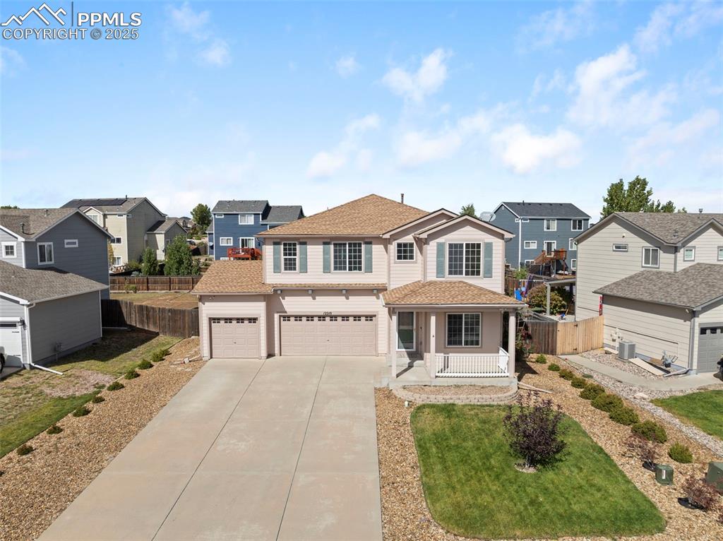 Traditional home with driveway, a residential view, a porch, and roof with shingles