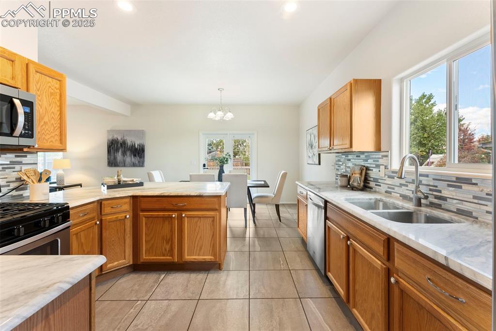 Kitchen with tasteful backsplash, a peninsula, a chandelier, appliances with stainless steel finishes, and recessed lighting
