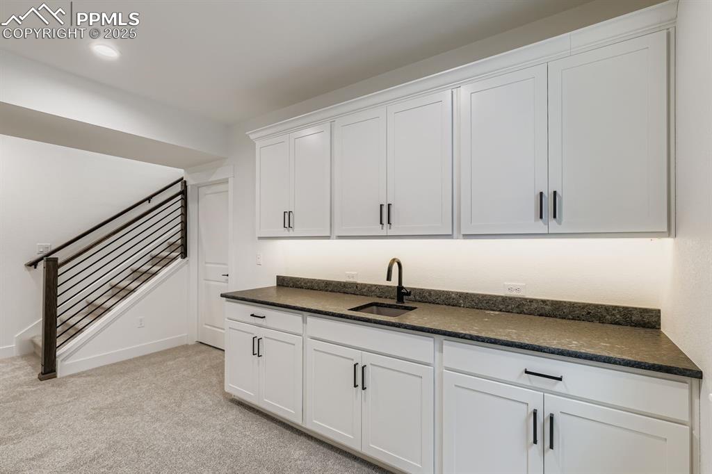 Kitchen featuring white cabinetry, light carpet, and dark stone counters