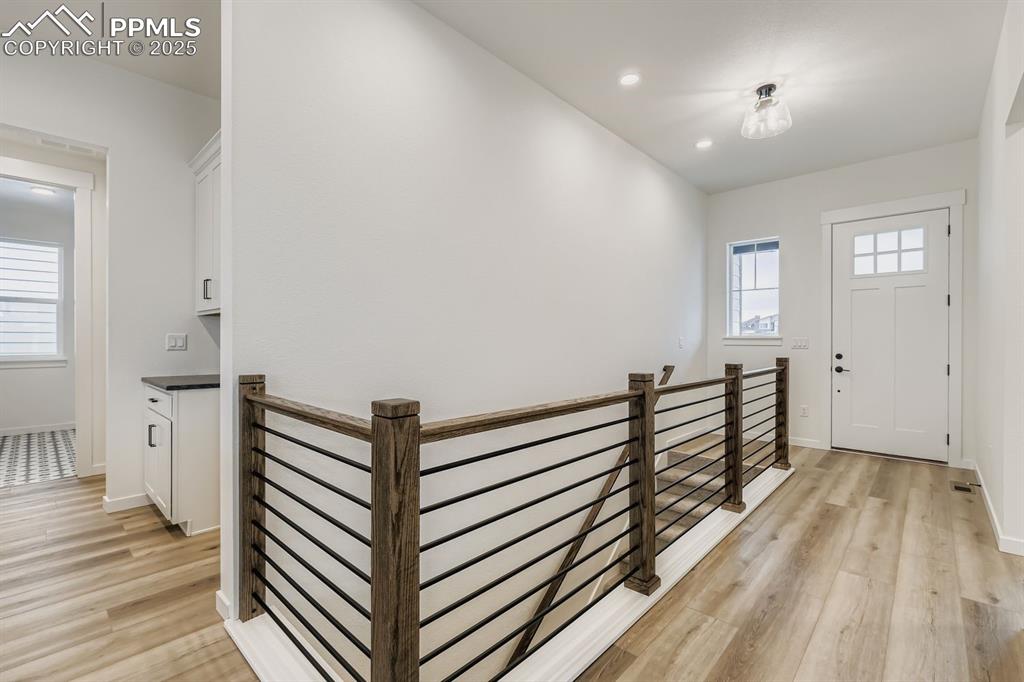 Corridor with an upstairs landing, light wood-style floors, and recessed lighting