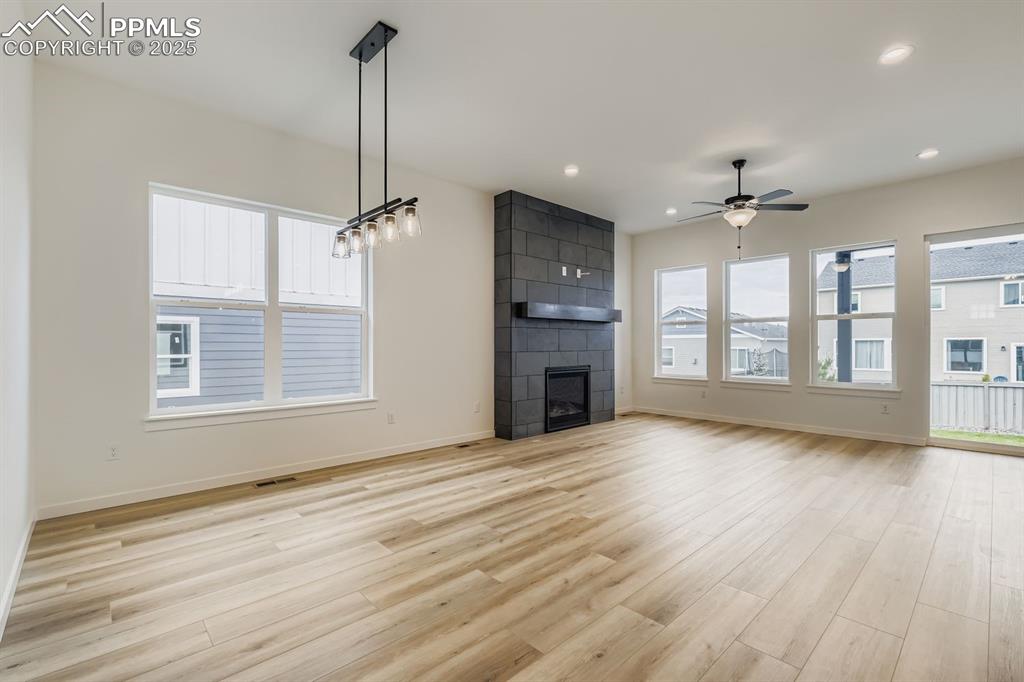 Unfurnished living room with a large fireplace, light wood-type flooring, recessed lighting, and a ceiling fan
