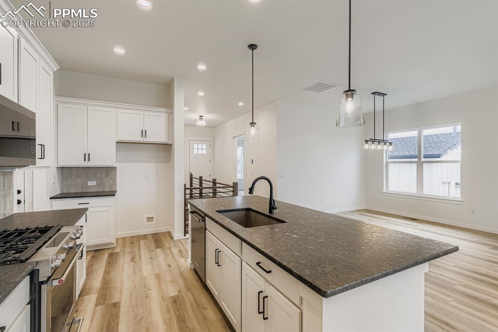Kitchen featuring stainless steel appliances, white cabinets, light wood finished floors, and recessed lighting