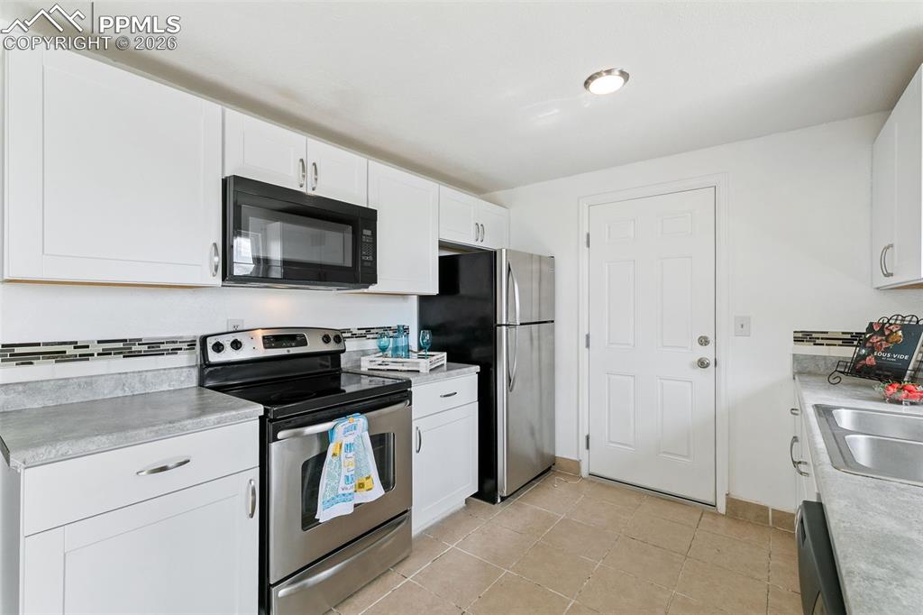 Kitchen featuring appliances with stainless steel finishes, light countertops, white cabinets, and light tile patterned floors