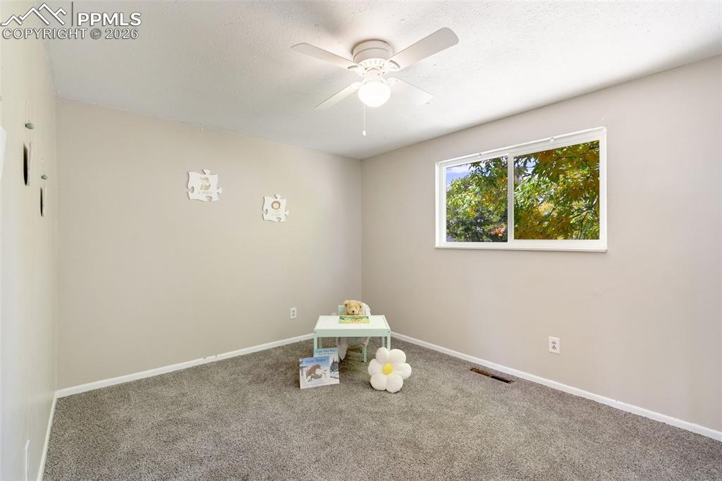 Carpeted empty room featuring a ceiling fan and a textured ceiling