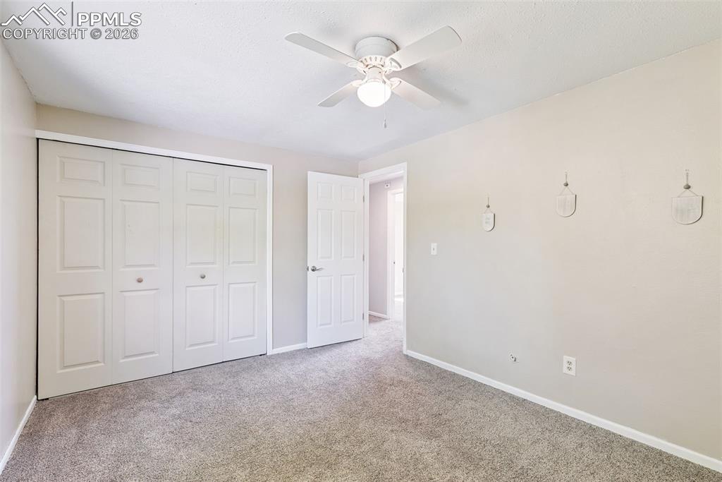 Unfurnished bedroom featuring a closet, carpet floors, and a ceiling fan