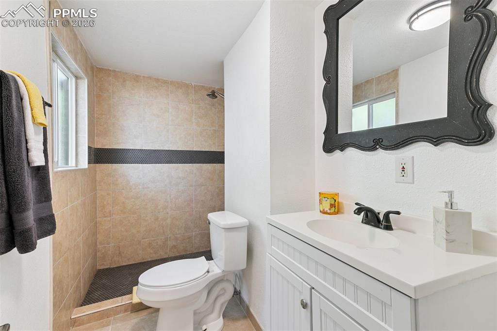 Full bath with vanity, a stall shower, healthy amount of natural light, and a textured wall