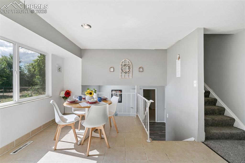 Dining space with light tile patterned floors and stairs