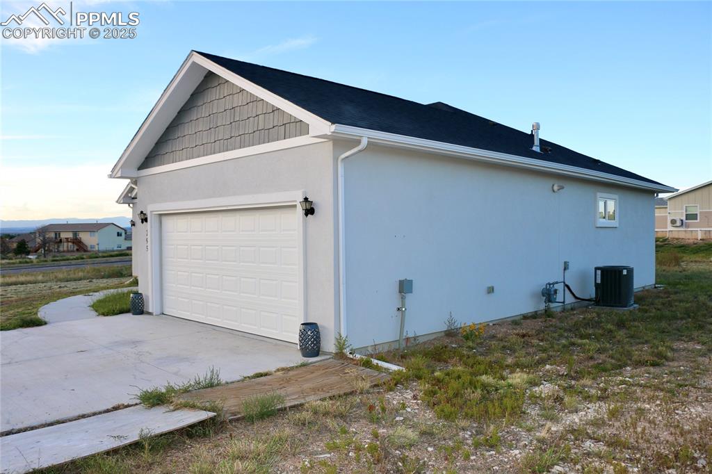 View of home's exterior with stucco siding, concrete driveway, and a garage