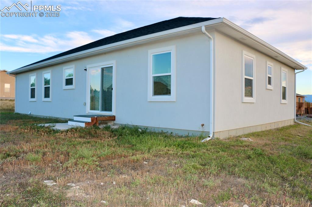 Rear view of property with a lawn and stucco siding
