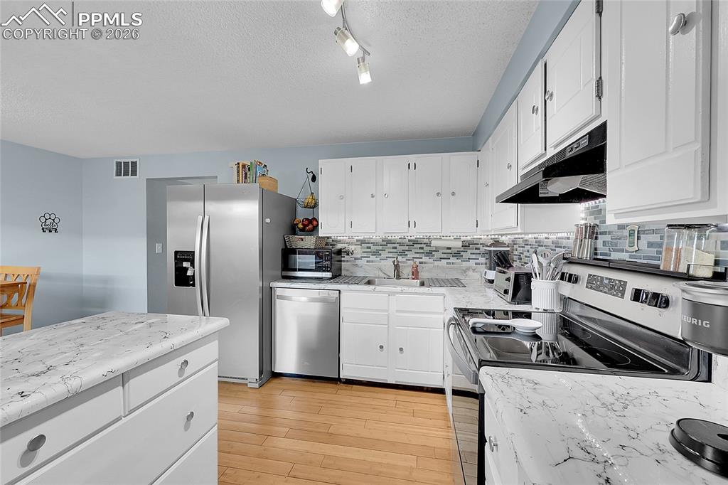 Another view of kitchen with newer countertops and beautiful hardwood flooring. 