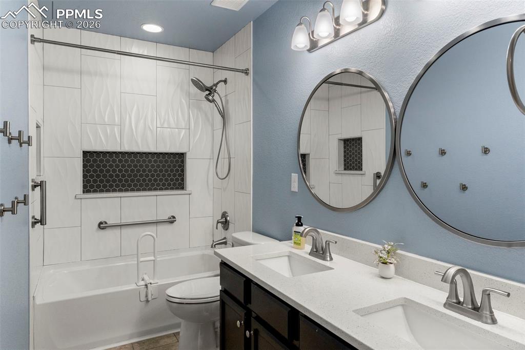 Bathroom featuring double vanity, tub / shower combination, and a textured wall