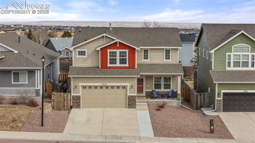 View of front facade featuring stone siding, a residential view, driveway, and an attached garage