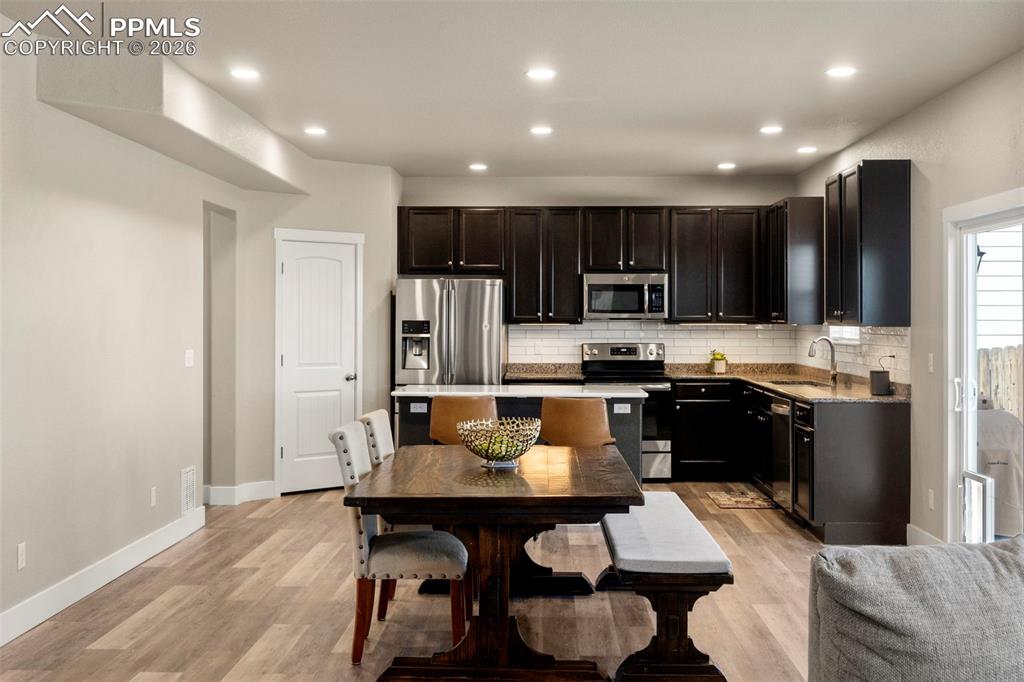 Kitchen with stainless steel appliances, recessed lighting, light stone countertops, light wood-style floors, and backsplash