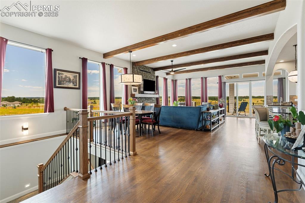 Living room with beamed ceiling, wood finished floors, arched walkways, and a ceiling fan