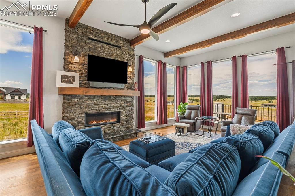 Living area with beam ceiling, wood finished floors, a fireplace, ceiling fan, and recessed lighting