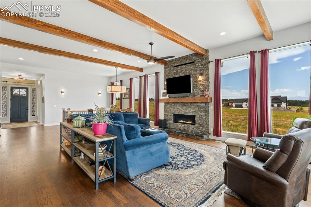 Living room featuring beam ceiling, healthy amount of natural light, wood finished floors, recessed lighting, and ceiling fan