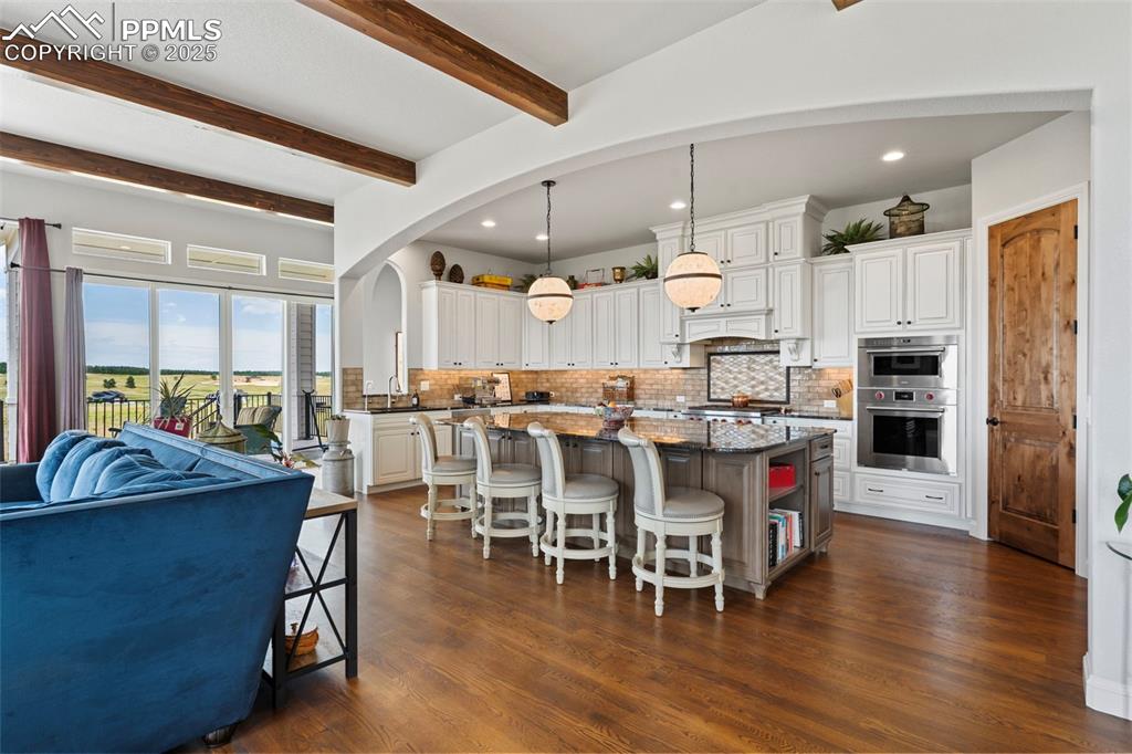Kitchen featuring pendant lighting, a breakfast bar, a kitchen island, white cabinets, and recessed lighting