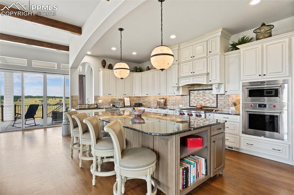 Kitchen with dark stone counters, a center island, decorative light fixtures, a breakfast bar, and decorative backsplash