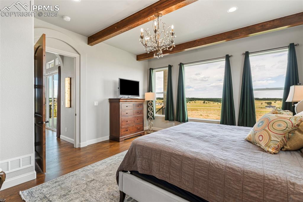 Bedroom featuring dark wood finished floors, arched walkways, recessed lighting, beamed ceiling, and a chandelier