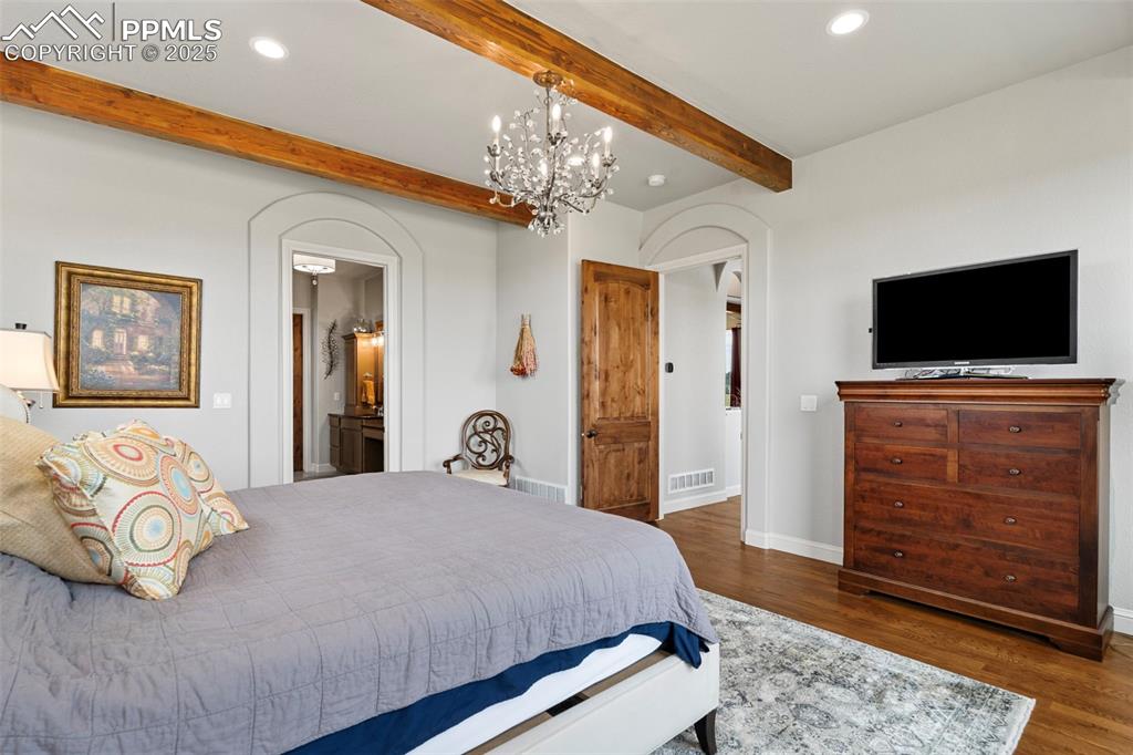 Bedroom with dark wood-style flooring, beamed ceiling, a chandelier, recessed lighting, and ensuite bathroom