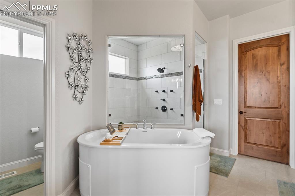 Bathroom with a soaking tub, light tile patterned floors, and tiled shower