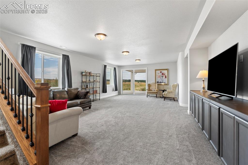 Living room featuring light carpet, a textured ceiling, and stairs