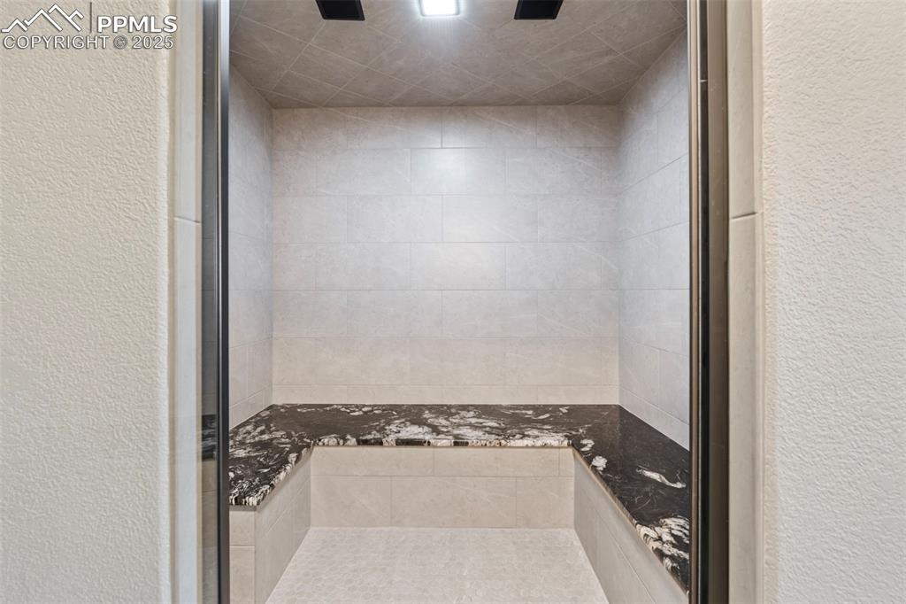 Bathroom featuring a textured wall and a shower stall