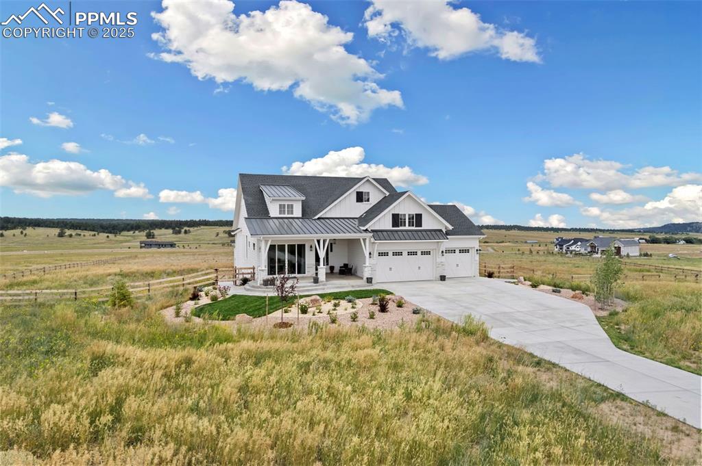 Modern inspired farmhouse featuring a rural view, a standing seam roof, a metal roof, and driveway