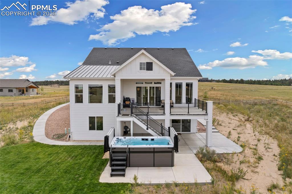 Back of house with a hot tub, stairs, a patio area, board and batten siding, and a shingled roof