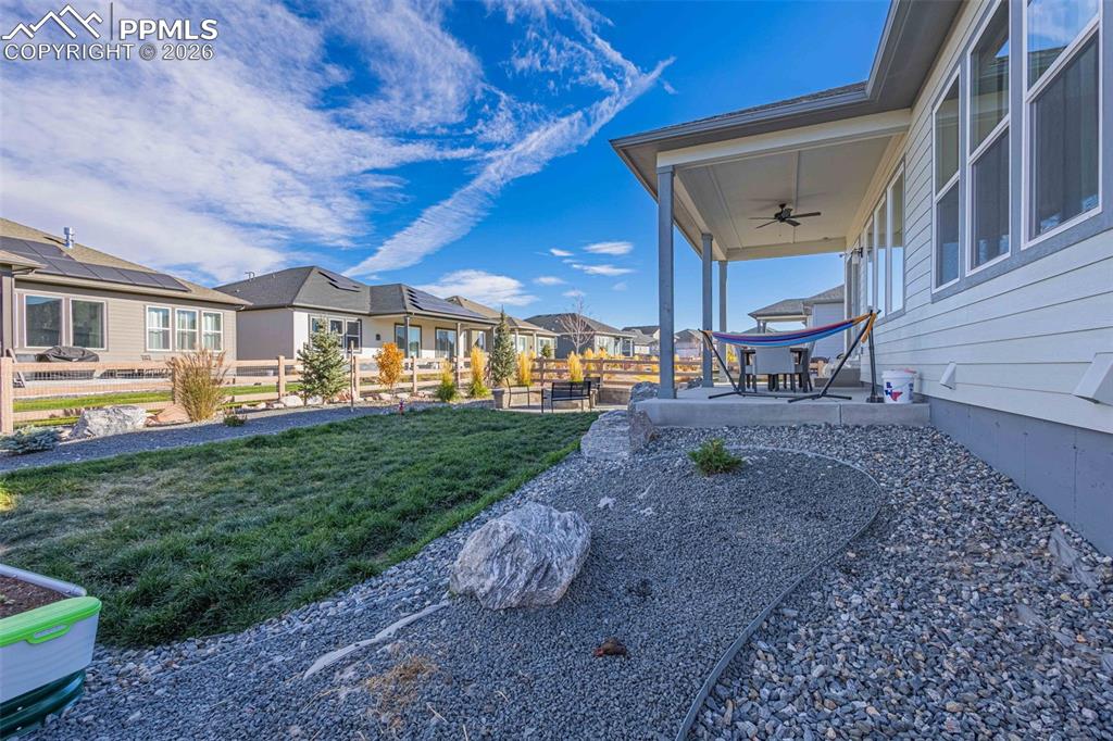 View of grassy yard featuring a residential view, a ceiling fan, and a patio