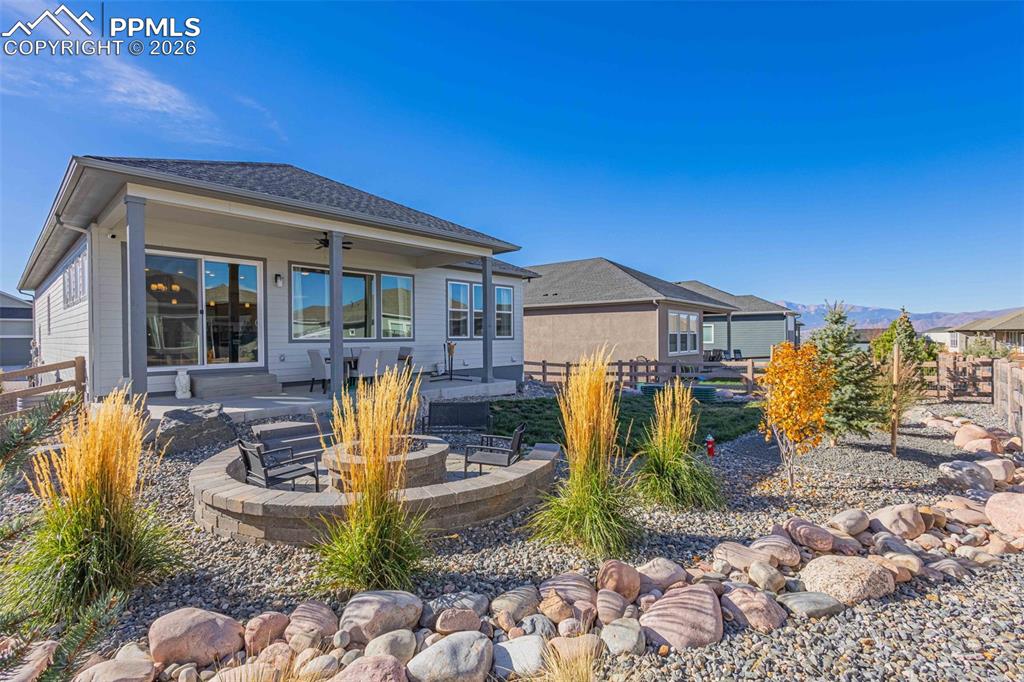 Back of house featuring a patio, a fire pit, a ceiling fan, and roof with shingles