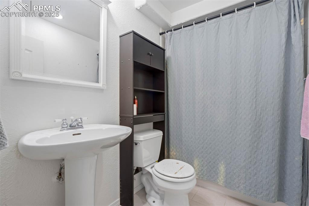 Bathroom featuring light tile patterned flooring, a shower with shower curtain, and a textured wall