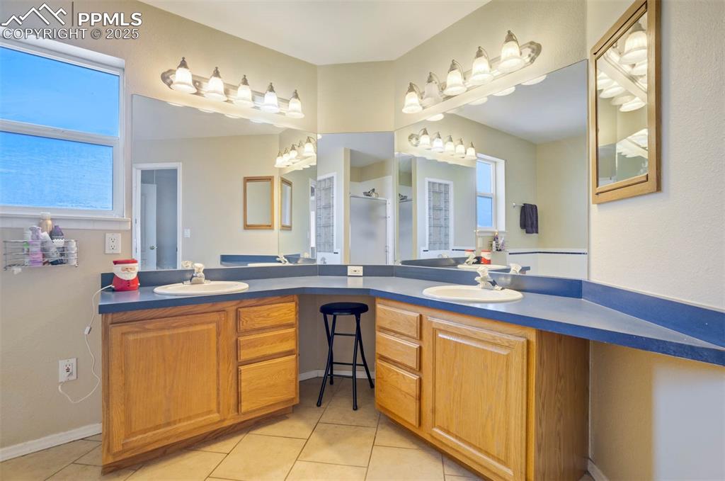 Full bathroom with double vanity, light tile patterned flooring, and a walk in shower